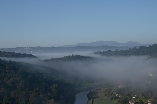 montagna settentrionale in alto con foresta verde e villaggio nebbioso che attraversa il fiume