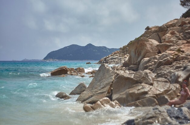 Montagna sul mare nel sud della Sardegna filtrata da una scogliera durante l'estate con le onde del mare