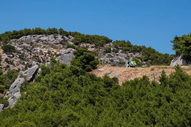 Montagne, croce bianca sull'alta collina e vecchio furgone nei graffiti, Grecia