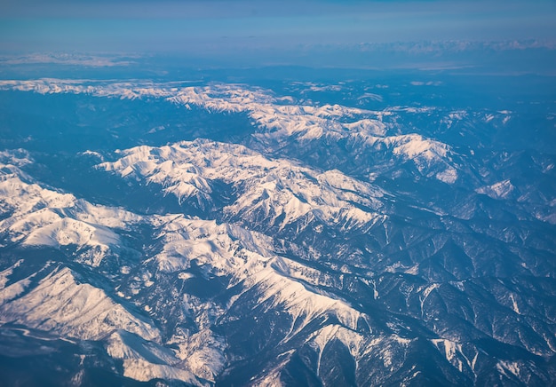 Montagne di picco invernale con neve dalla finestra dell'aereo.