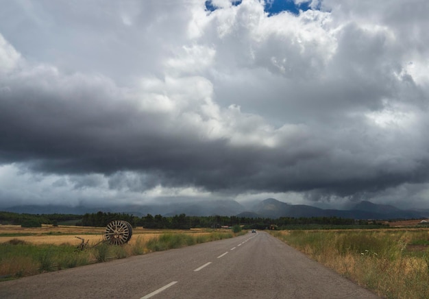 Montagne e campi della foresta della strada nel villaggio greco in una tempesta estiva con nuvole nere in Grecia
