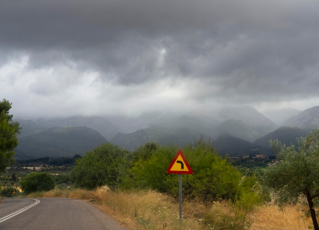 Montagne e campi della foresta della strada nel villaggio greco in una tempesta estiva con nuvole nere in Grecia