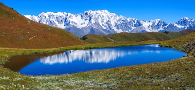 Montagne e lago su sfondo blu con cielo nuvoloso. Paesaggio