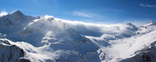 Montagne innevate tra le nuvole cielo blu Caucaso Elbrus