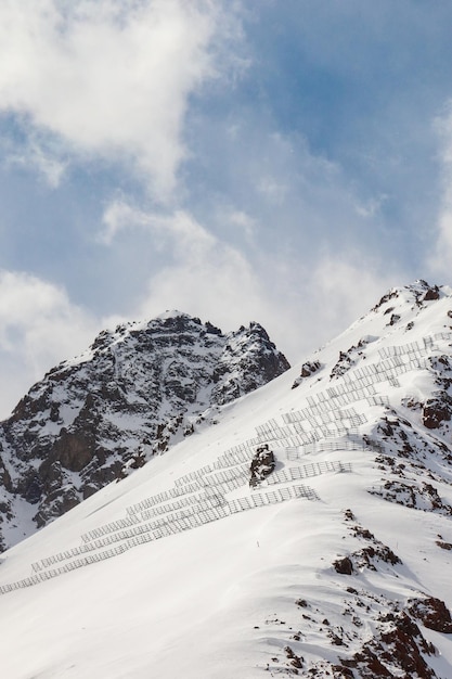 Montagne rocciose innevate con barriere di protezione contro le valanghe spazio copia verticale