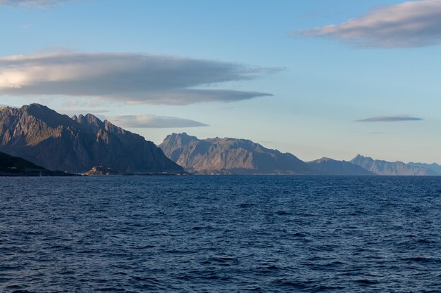 Montagne verdi con il mare sulla riva e nuvole nel cielo