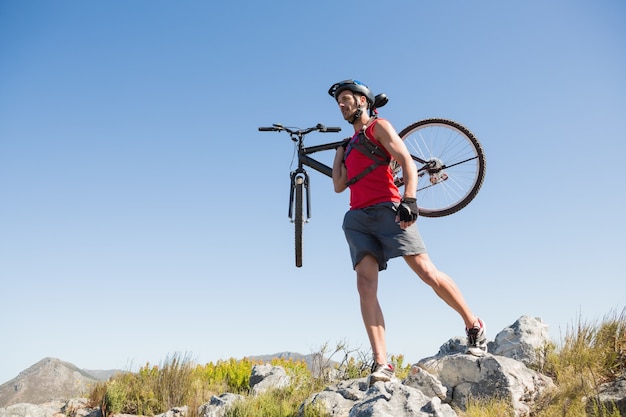 Montare il ciclista che porta la sua bici su terreno roccioso