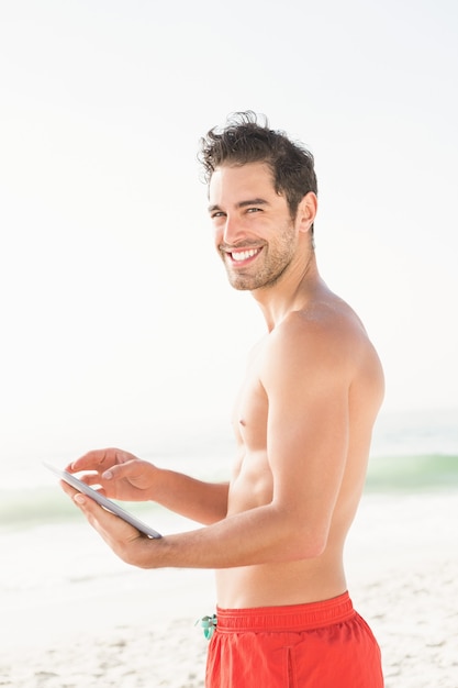 Montare l'uomo utilizzando tablet sulla spiaggia