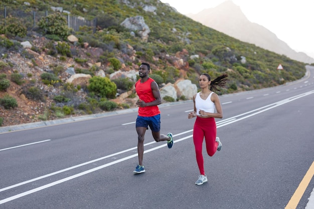 Montare la coppia afroamericana in abbigliamento sportivo che corre su una strada costiera. stile di vita sano, esercizio in natura.