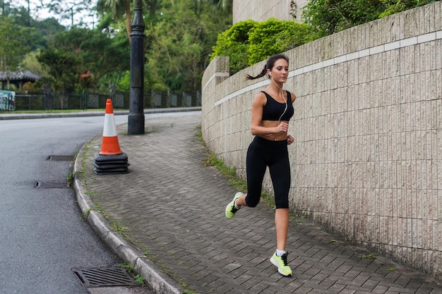 Montare la giovane donna che pareggia jogging sul marciapiede nella zona suburbana Bella ragazza che lavora all'aperto