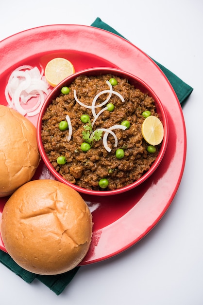 Montone Kheema Pav O Carne macinata piccante indiana servita con pane O kulcha, guarnita con piselli. Sfondo lunatico. Messa a fuoco selettiva