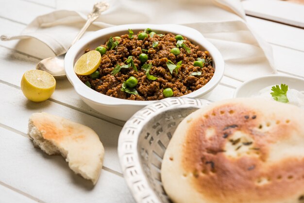 Montone Kheema Pav O Carne macinata piccante indiana servita con pane O kulcha, guarnita con piselli. Sfondo lunatico. Messa a fuoco selettiva