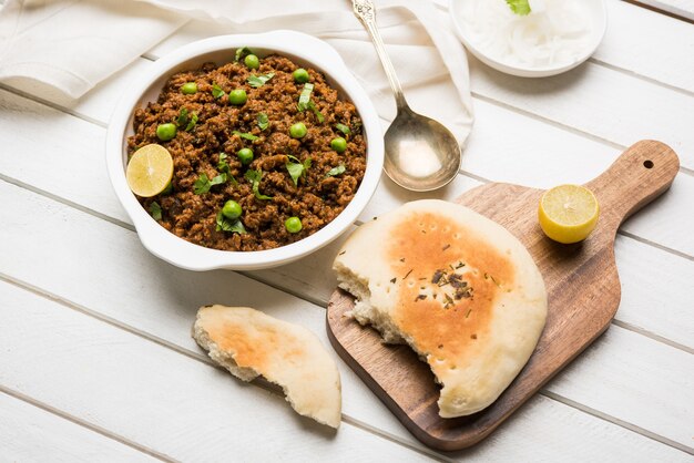 Montone Kheema Pav O Carne macinata piccante indiana servita con pane O kulcha, guarnita con piselli. Sfondo lunatico. Messa a fuoco selettiva