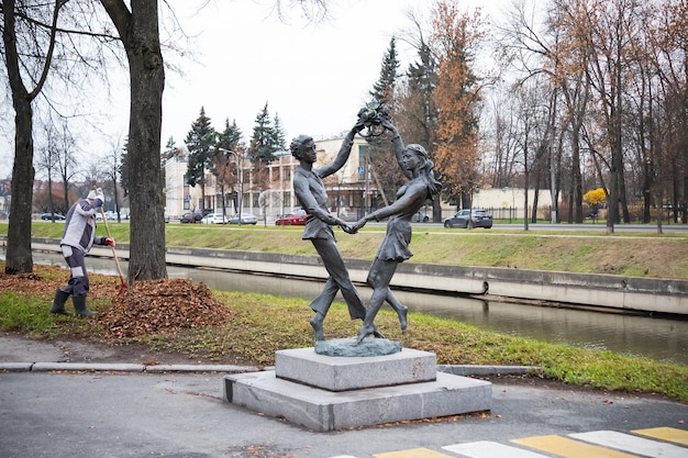 Monumento alla coppia innamorata e allo spazzino che rimuove le foglie cadute sullo sfondo della strada della città