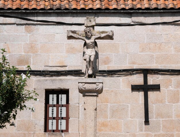 Monumento in pietra di un Cristo crocifisso al centro di una piazza di una città galiziana illuminata dal
