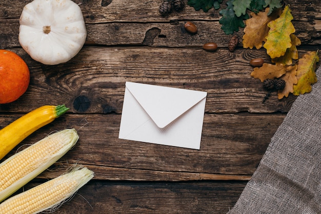 Mood autunnale: lettera, zucche e mais con foglie gialle su legno