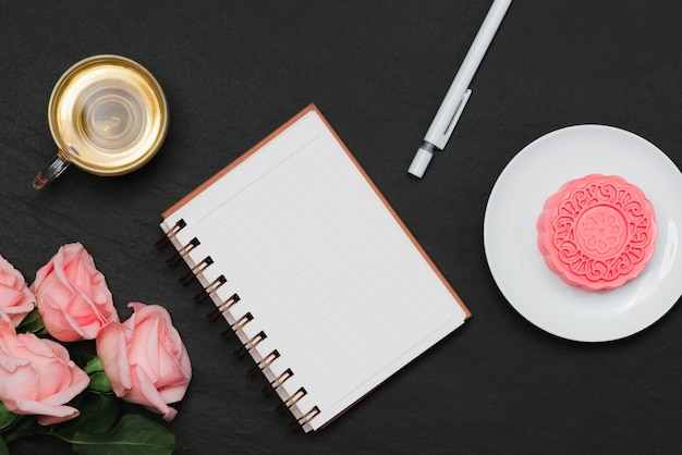 Mooncake con pelle di neve e tazza da tè con fiori. Apra il taccuino con copia-spazio.