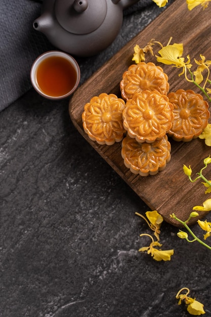 Mooncake Moon cake per MidAutumn Festival concetto di tradizionale cibo festivo su tavola di ardesia nera con tè e fiore giallo primo piano spazio di copia