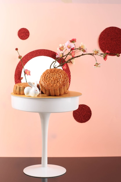 Mooncake su sfondo rosa chiaro con fiore rosa. Torta della luna di concetto sul festival di metà autunno. Mooncake Popolare come Kue Bulan.