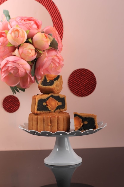 Mooncake su sfondo rosa chiaro con fiore rosa. Torta della luna di concetto sul festival di metà autunno. Mooncake Popolare come Kue Bulan.