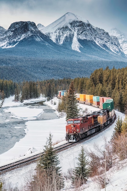 Morants Curve con l'iconico treno merci rosso che passa attraverso la valle dell'arco e le montagne rocciose in inverno al parco nazionale di Banff