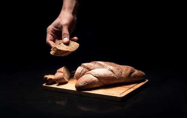 Morbido e croccante. Chiuda in su delle mani dell'uomo che tengono la baguette durante la cottura e la preparazione di un piatto in un ristorante.