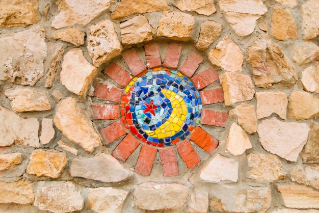 Mosaico circolare Solorfull con un simbolo religioso sul muro di pietra