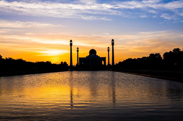 Moschea centrale di Songkhla dal giorno alla notte con cieli colorati al tramonto e le luci della moschea e i riflessi nell'acqua nel concetto di paesaggio di riferimento