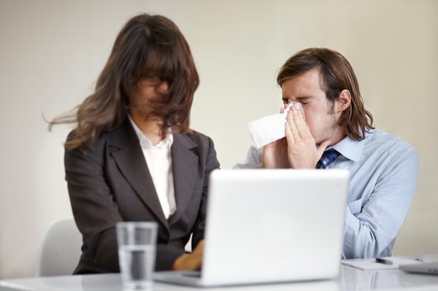 Mostrando cattive maniere Un giovane uomo d'affari che soffia il naso in tutto un collega