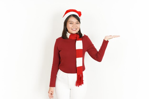 Mostrando e presentando il prodotto sul palmo aperto di una donna asiatica che indossa un dolcevita rosso e un cappello da Babbo Natale