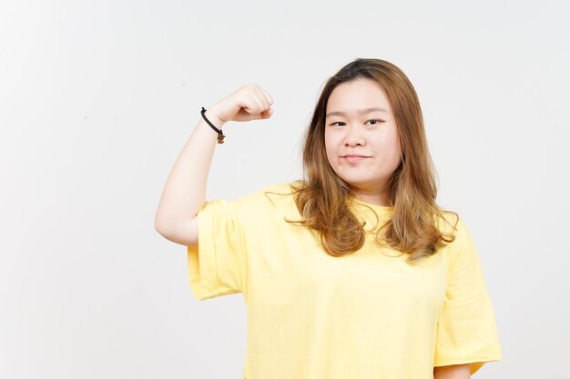 Mostrando le braccia di forza della bella donna asiatica che indossa una maglietta gialla isolata su sfondo bianco