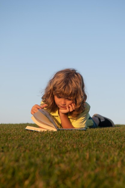 Motivazione scolastica all'aperto apprendimento bambini bambino sta leggendo un libro sul parco primaverile rilassandosi su t