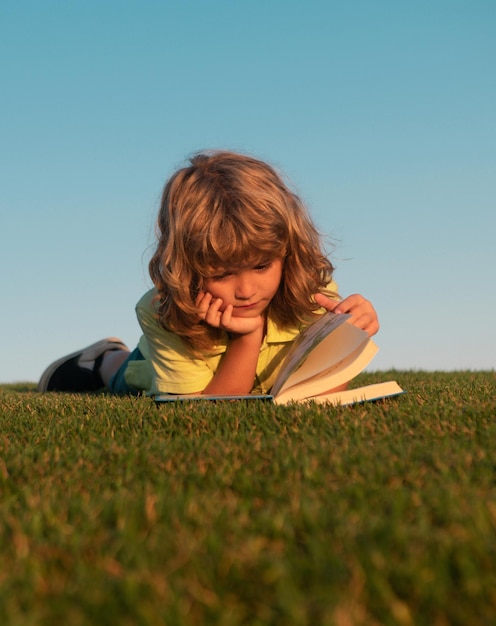 Motivazione scolastica all'aperto apprendimento bambini bambino sta leggendo un libro sul parco primaverile rilassandosi su t