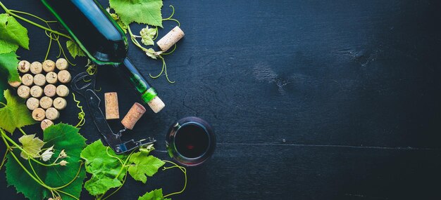 Motivo dell'uva. Una bottiglia e un bicchiere di vino e foglie di vite. Vista dall'alto. Spazio libero.