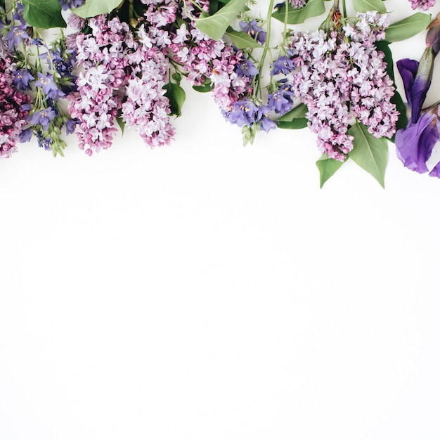 Motivo floreale con fiore lilla, fiore di iris viola, foglie verdi, rami su bianco