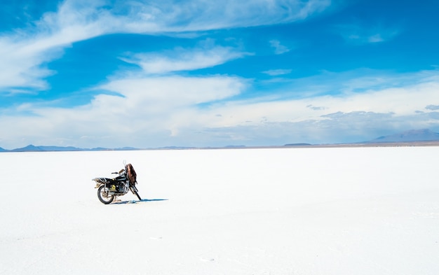 Moto sullo sfondo del sole spazioso Salar de Uyuni