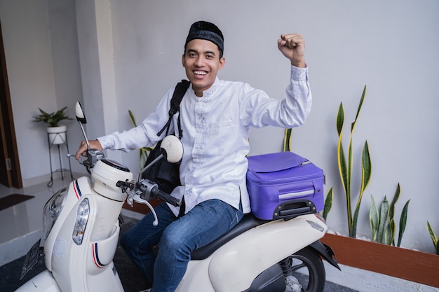 Moto uomo musulmano in sella per valigia da trasporto idul fitri balik kampung mudik