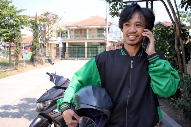 Motocicletta asiatica del tassista online che riceve una telefonata dal cliente