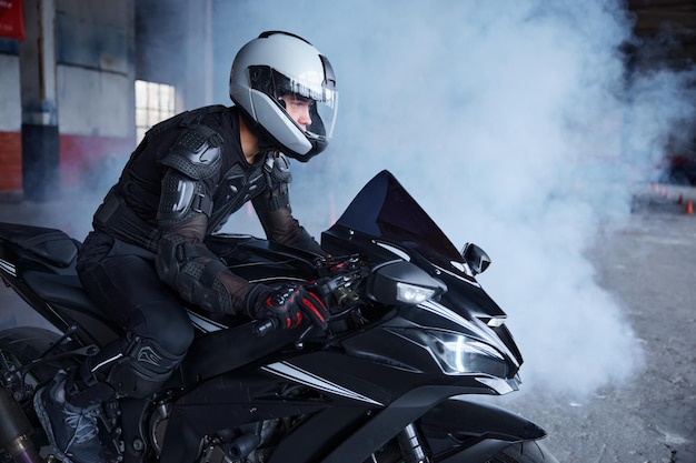 Motociclista che indossa casco protettivo e uniforme per la guida di velocità in classe di addestramento