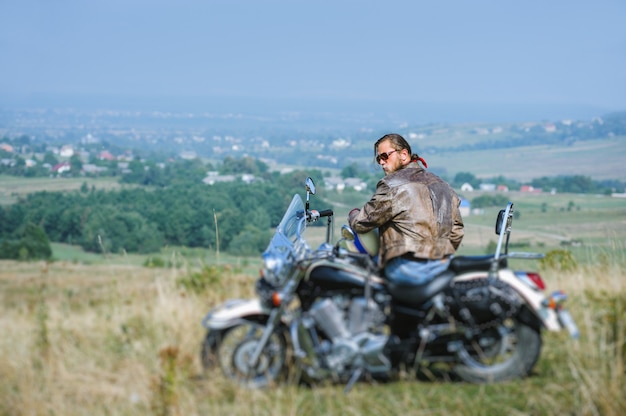 Motociclista con la barba seduto sulla sua moto in una giornata di sole