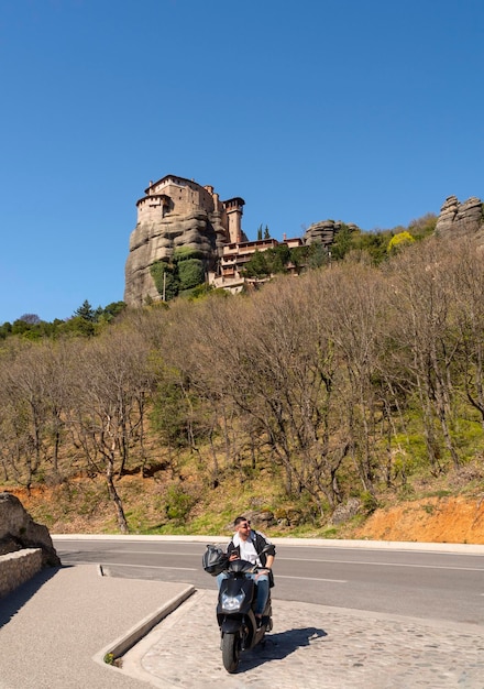 Motociclista e vista delle montagne di Meteora e del monastero di Rusanou dal ponte di osservazione in Grecia
