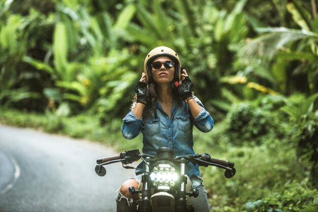 Motociclista femmina alla guida di una moto cafe racer