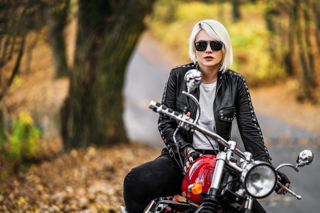 Motociclista femminile abbastanza biondo con una motocicletta rossa