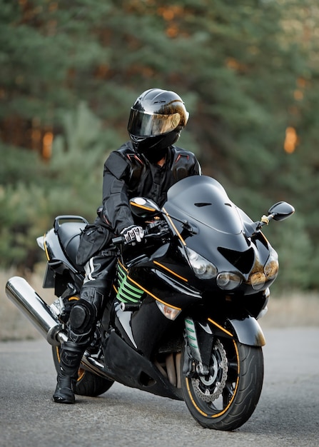 Motociclista in un casco su una moto su una strada di campagna.