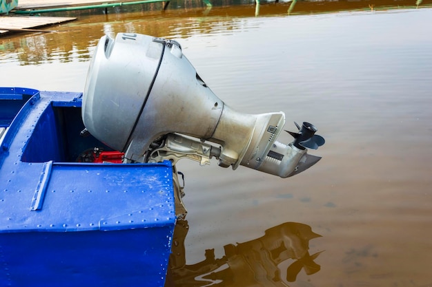 Motore fuoribordo su una barca da pesca in alluminio blu Motore fuoribordo su una barca da diporto sul fiume del lago