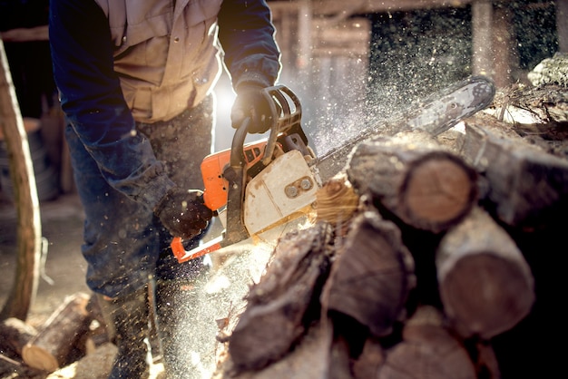 Motosega in azione tagliando legno. Uomo che taglia il legno con sega, polvere e movimenti.