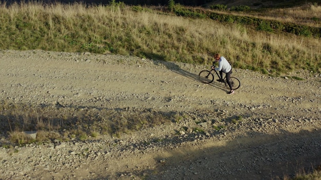 Mountain bike in sella a un drone vista sentiero roccioso erboso caldo soleggiato giorno d'estate vacanza Scena tranquilla uomo in bicicletta tra l'erba che trascorre il tempo di viaggio facendo sport Concetto di avventura attività motociclista all'aperto