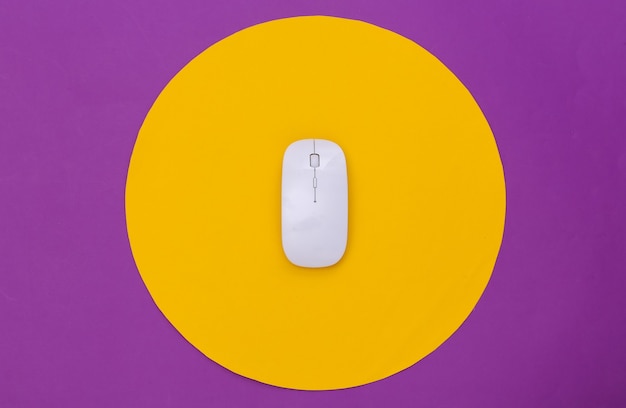 Mouse pc bianco su sfondo viola con cerchio giallo. Colpo concettuale dello studio. Minimalismo. Vista dall'alto