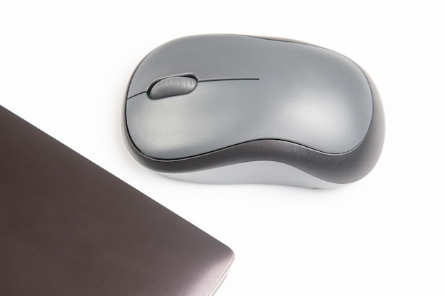 Mouse wireless per computer accanto a un computer portatile su un tavolo bianco primo piano industria elettronica personale