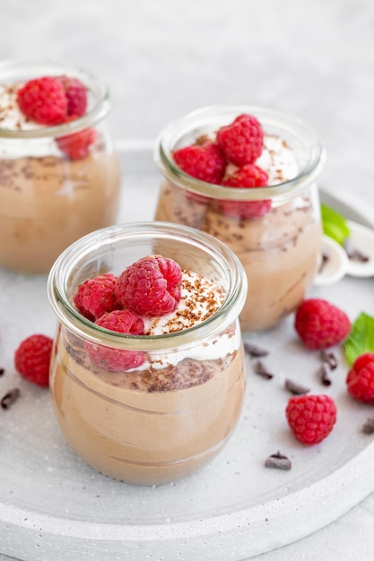 Mousse al cioccolato con panna montata e lamponi freschi in un bicchiere Copia spazio